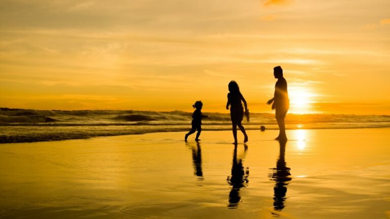 Silhueta de uma família caminhando na praia ao pôr do sol