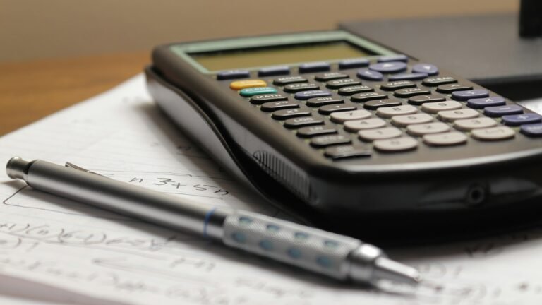 Calculadora e caneta sobre documentos