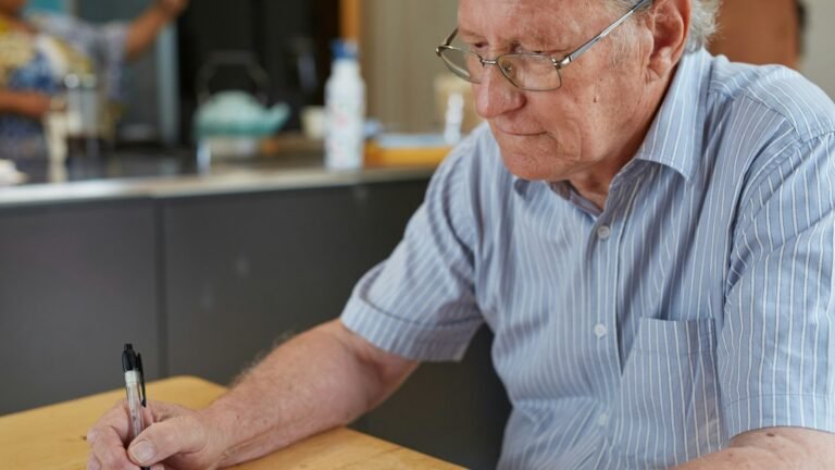 Homem idoso escrevendo em papéis sobre a mesa